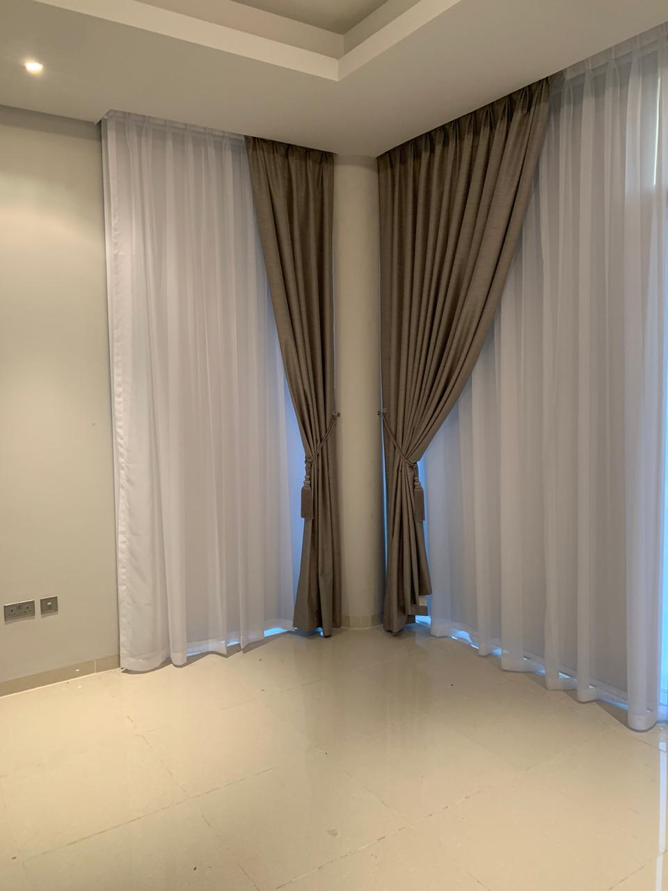 floor-to-ceiling sheer and blackout curtains dressed across a corner window
