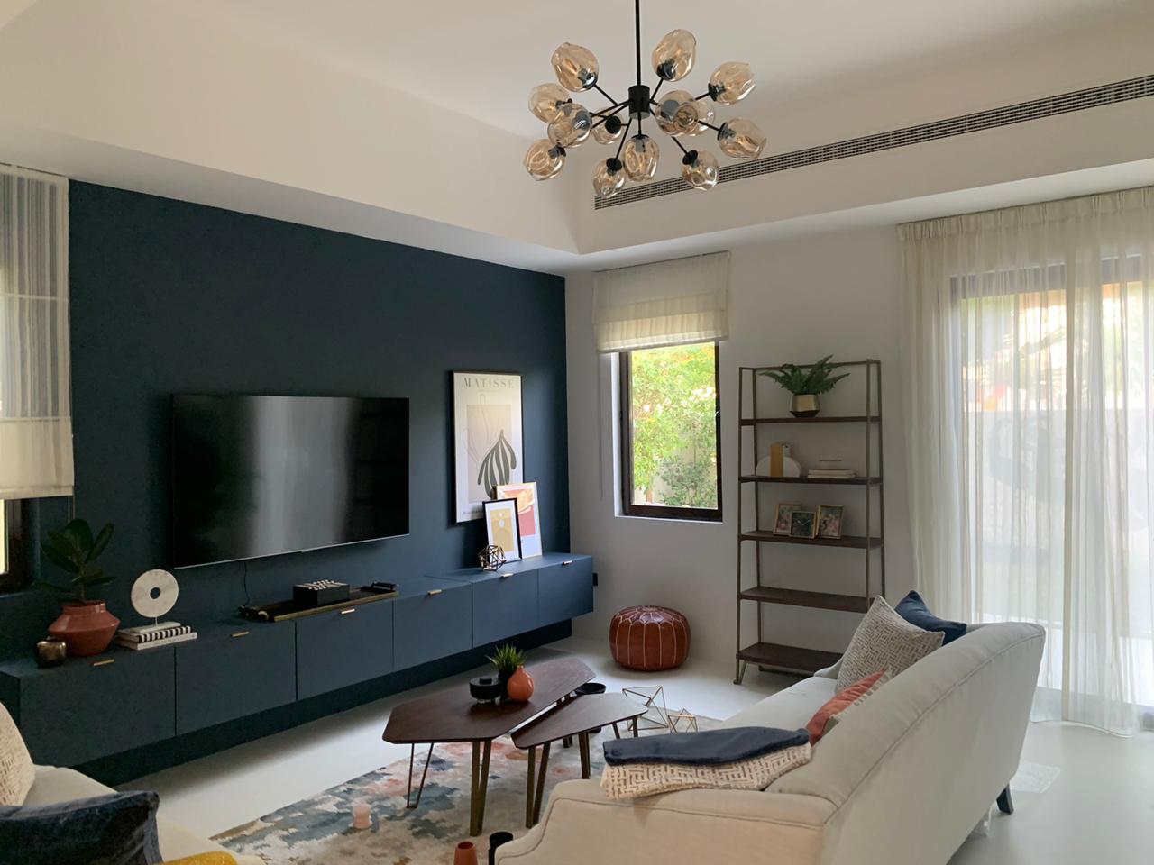living room with sheers, roman blinds, and a dark blue feature wall