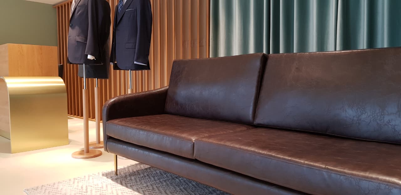 brown leather sofa in a premium showroom setting with curtains and timber detailing