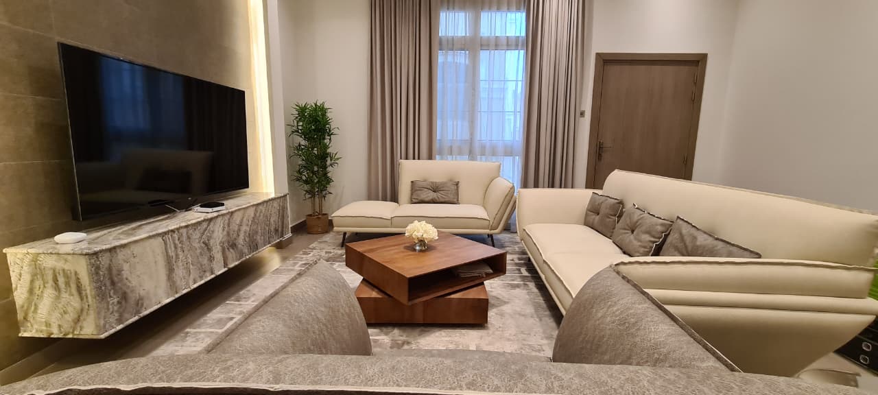 lounge with cream seating, a dark blue media wall, and layered window treatments