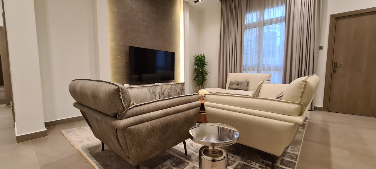 tailored lounge with upholstered seating, marble media wall, and floor-length drapery